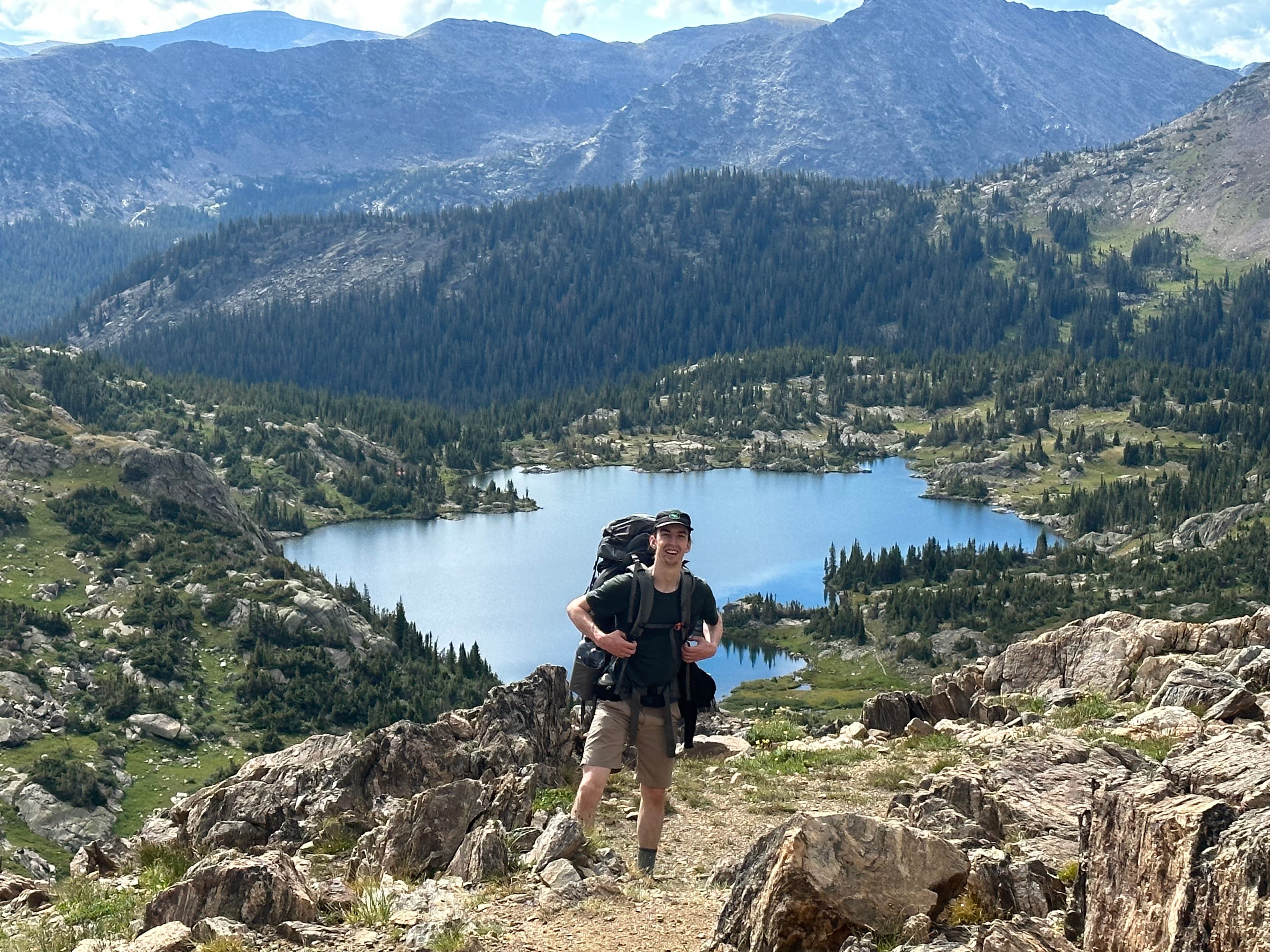 Zach standing in front of a lake and mountain view.